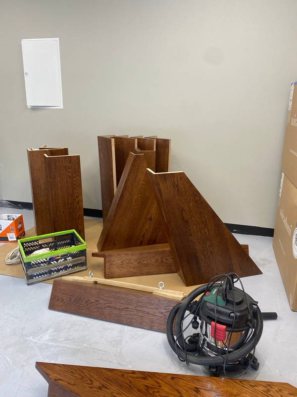 Elementy drewniane, prawdopodobnie schodów, w trakcie montażu, widoczny odkurzacz warsztatowy i skrzynka narzędziowa. Detal wykończenia z bliska.