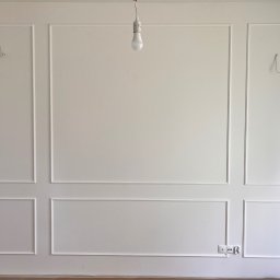 sunrise - Biała ściana z dekoracyjnymi listwami w stylu klasycznym, świeżo po remoncie w Gdańsku. Widoczne gniazdka elektryczne i prowizoryczne oświetlenie.