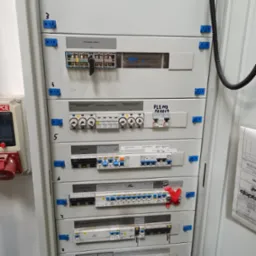 Rozdzielnica elektryczna z wyłącznikami, bezpiecznikami i oznaczeniami, widok z bliska na zamontowane zabezpieczenia i komponenty elektryczne.