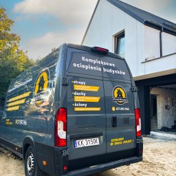 HEATHOUSE SPÓŁKA Z OGRANICZONĄ ODPOWIEDZIALNOŚCIĄ - Szary bus firmy HeatHouse z reklamą kompleksowego ocieplania budynków na tle domu w trakcie ocieplania. Widoczny numer telefonu i hasło 'Działamy w całej Polsce!'.