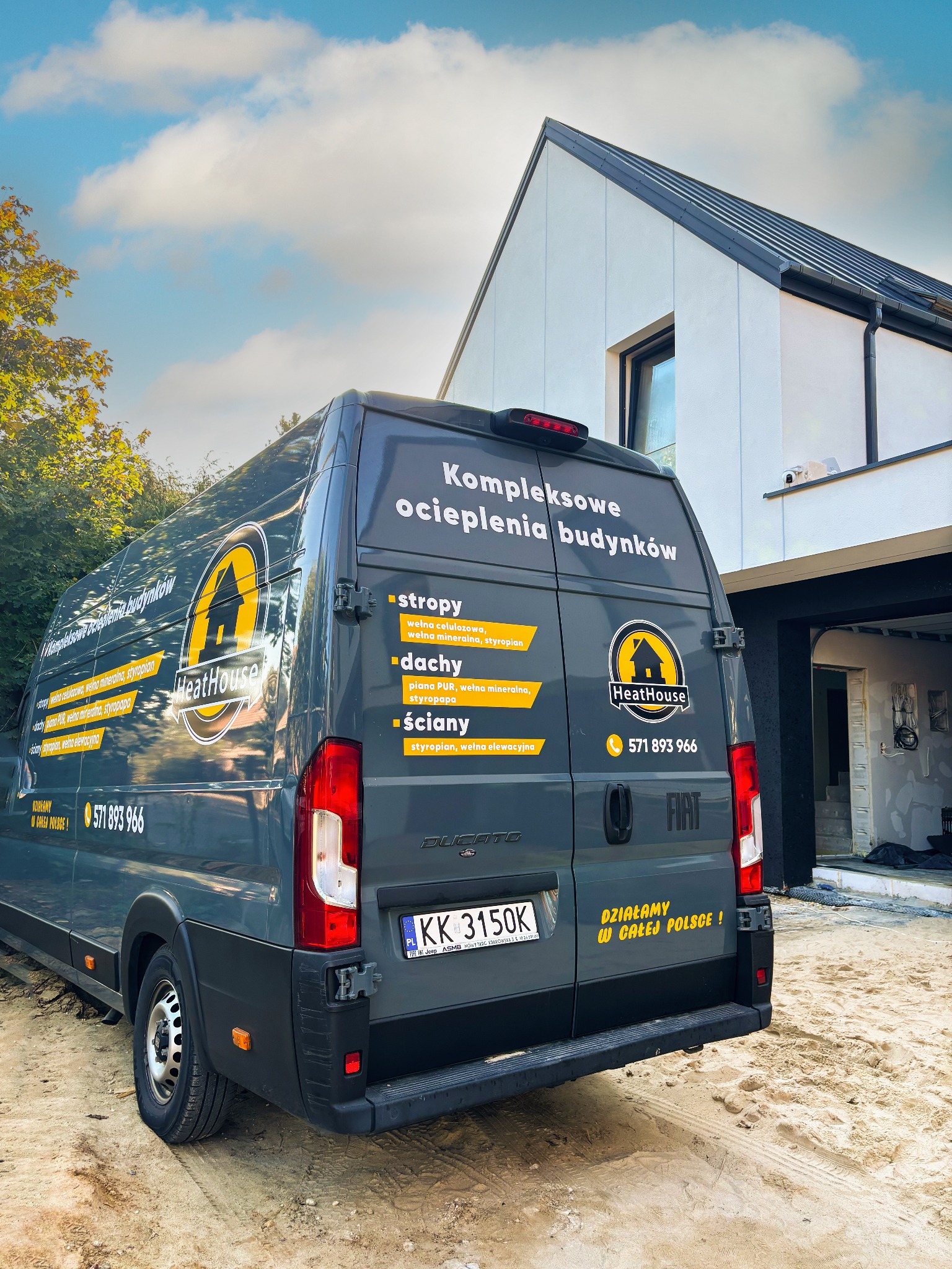 Szary bus firmy HeatHouse z reklamą kompleksowego ocieplania budynków na tle domu w trakcie ocieplania. Widoczny numer telefonu i hasło 'Działamy w całej Polsce!'.
