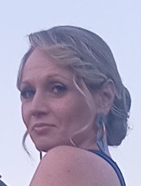 Portret kobiety z dużymi kolczykami, patrzy w bok. Uśmiech na twarzy, Siedlce. Zdjęcie z lekkim ziarnem, miękkie oświetlenie, skupienie na twarzy.