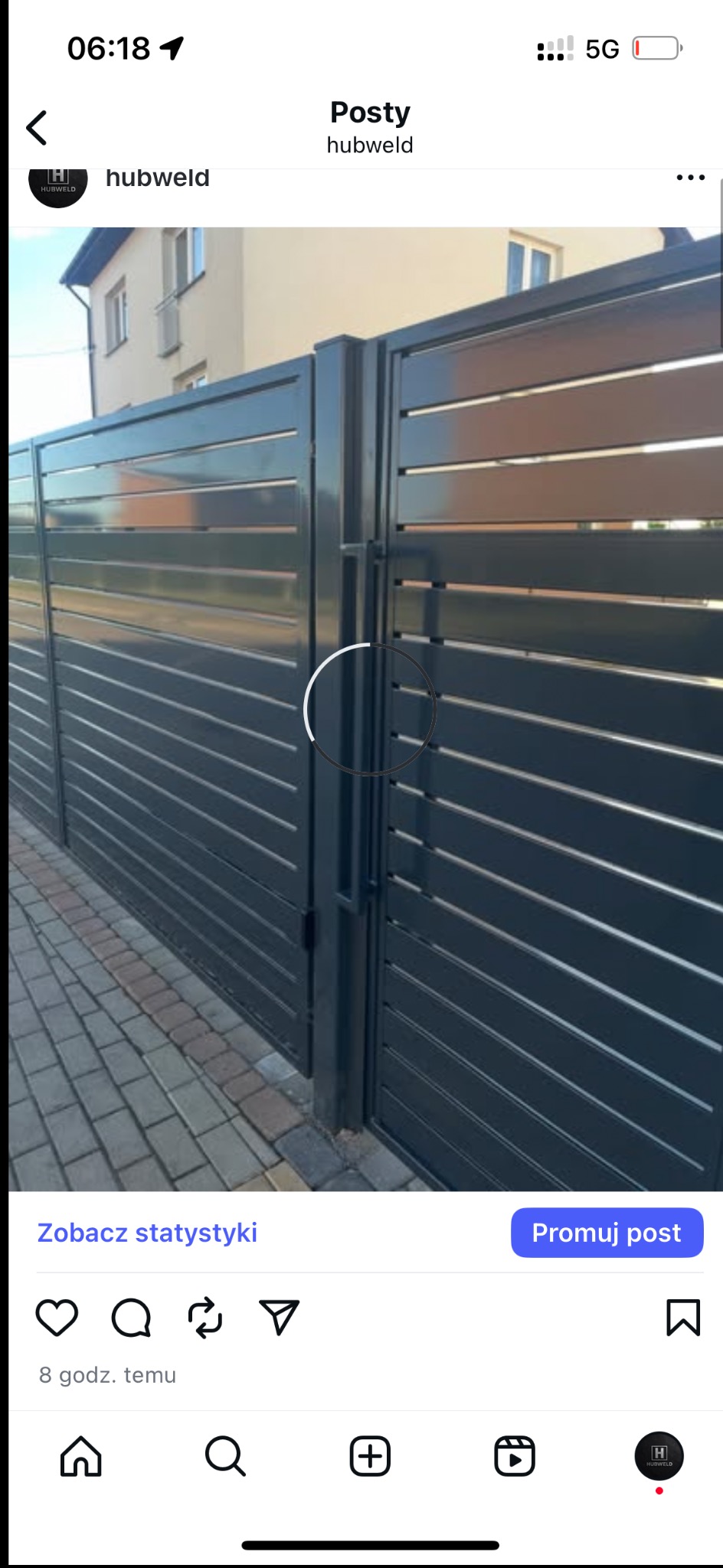 Nowoczesna brama wjazdowa z poziomych profili, pomalowana na grafitowo, z widocznym zamkiem i fragmentem kostki brukowej. Minimalistyczny design.