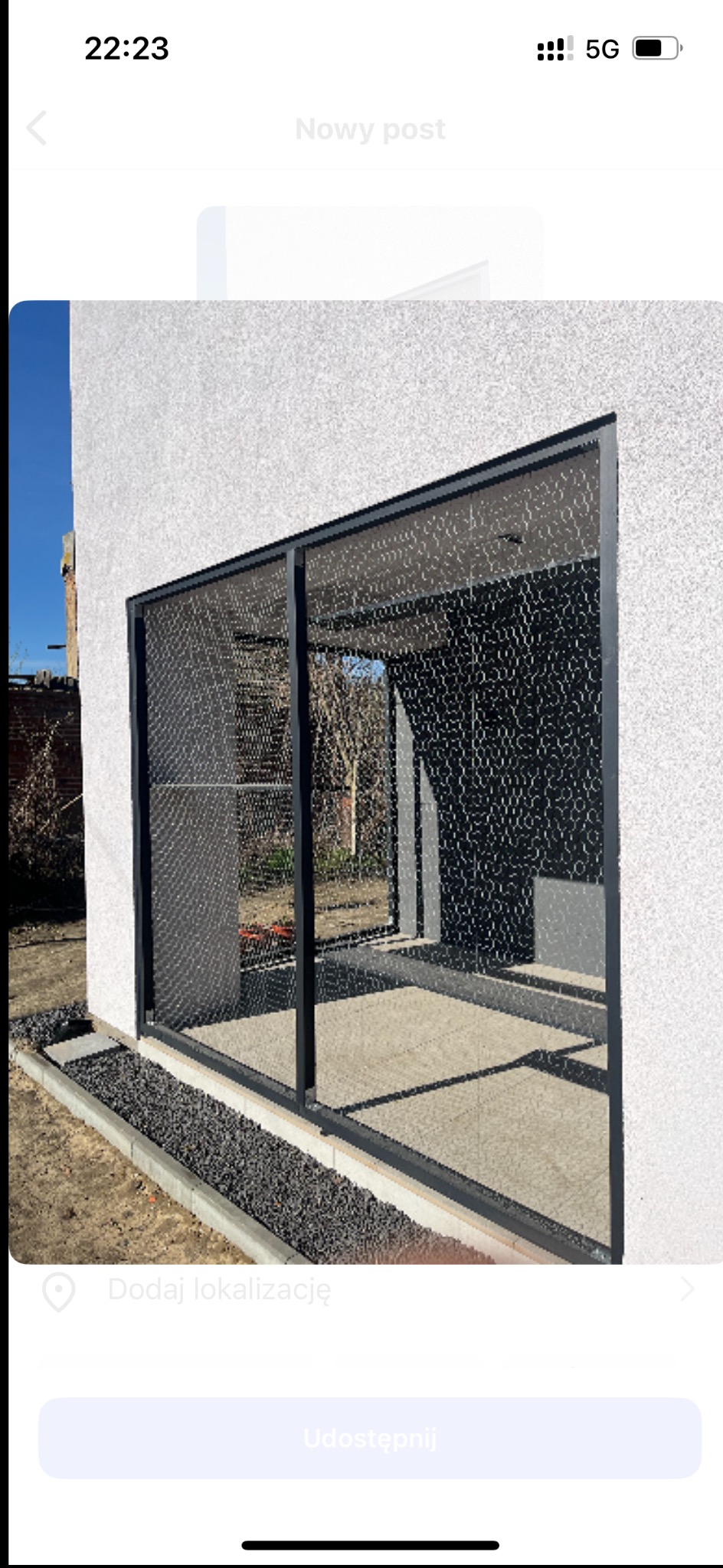 Metalowa pergola z dekoracyjnym wypełnieniem w Szczuczynie. Nowoczesna konstrukcja przy budynku z jasnym tynkiem i kamiennym obrzeżem.