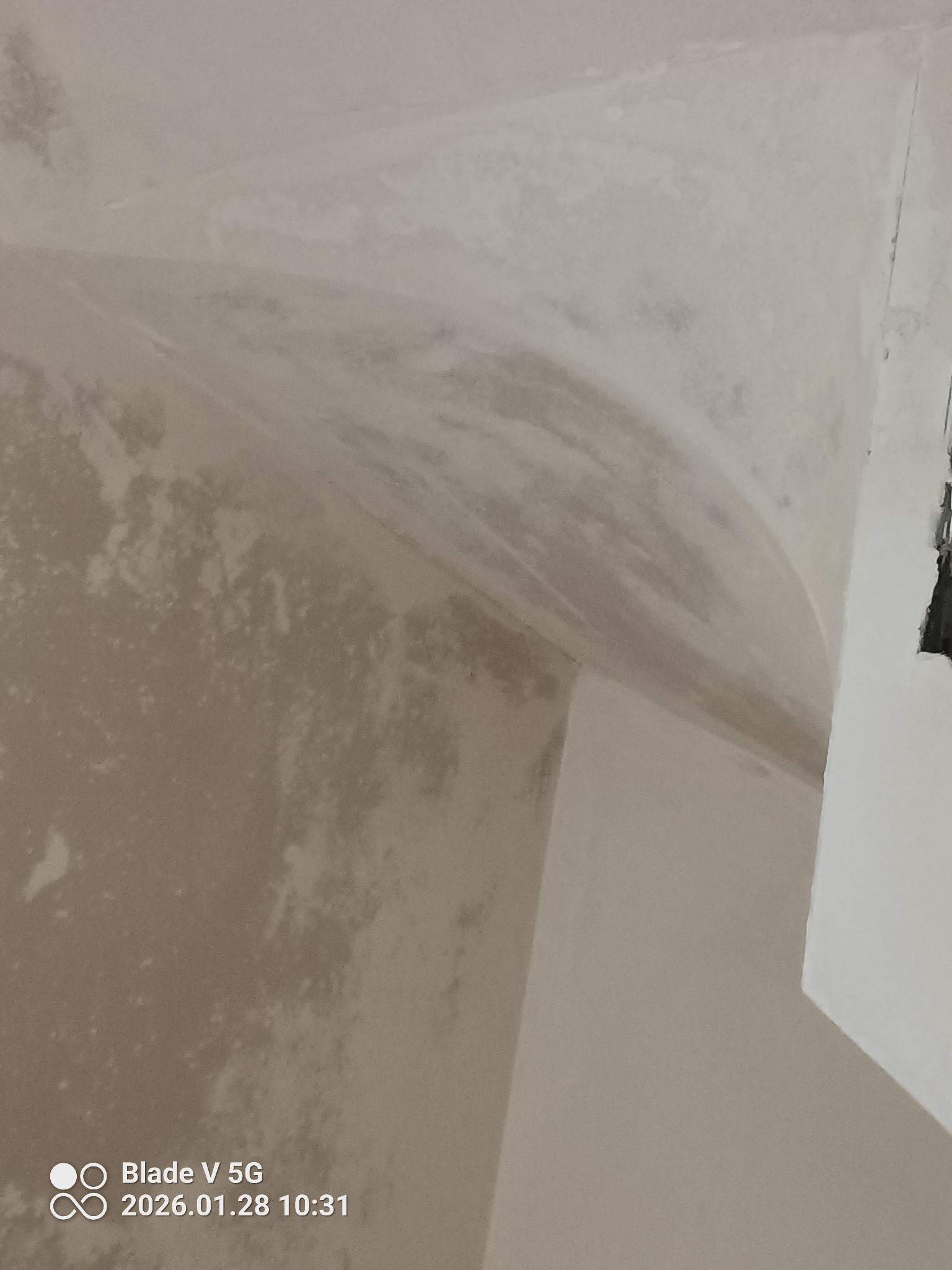 Niedokończone tynki na suficie i ścianie, widoczne nierówności i zacieki. Fragment okna w prawym górnym rogu. Ujęcie z dołu, blisko powierzchni.