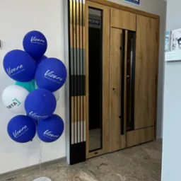 Wystawka drzwi Gerda z drewnianym wykończeniem i czarnymi elementami, obok balony z logo Vizera i Orta, prezentacja w salonie.