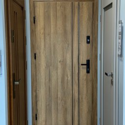 Vizera Sp. z o.o. - Drewnopodobne drzwi marki Doorpol z czarnymi akcentami, widoczne między innymi drzwiami w ekspozycji. Proste, matowe wykończenie, nowoczesny design.