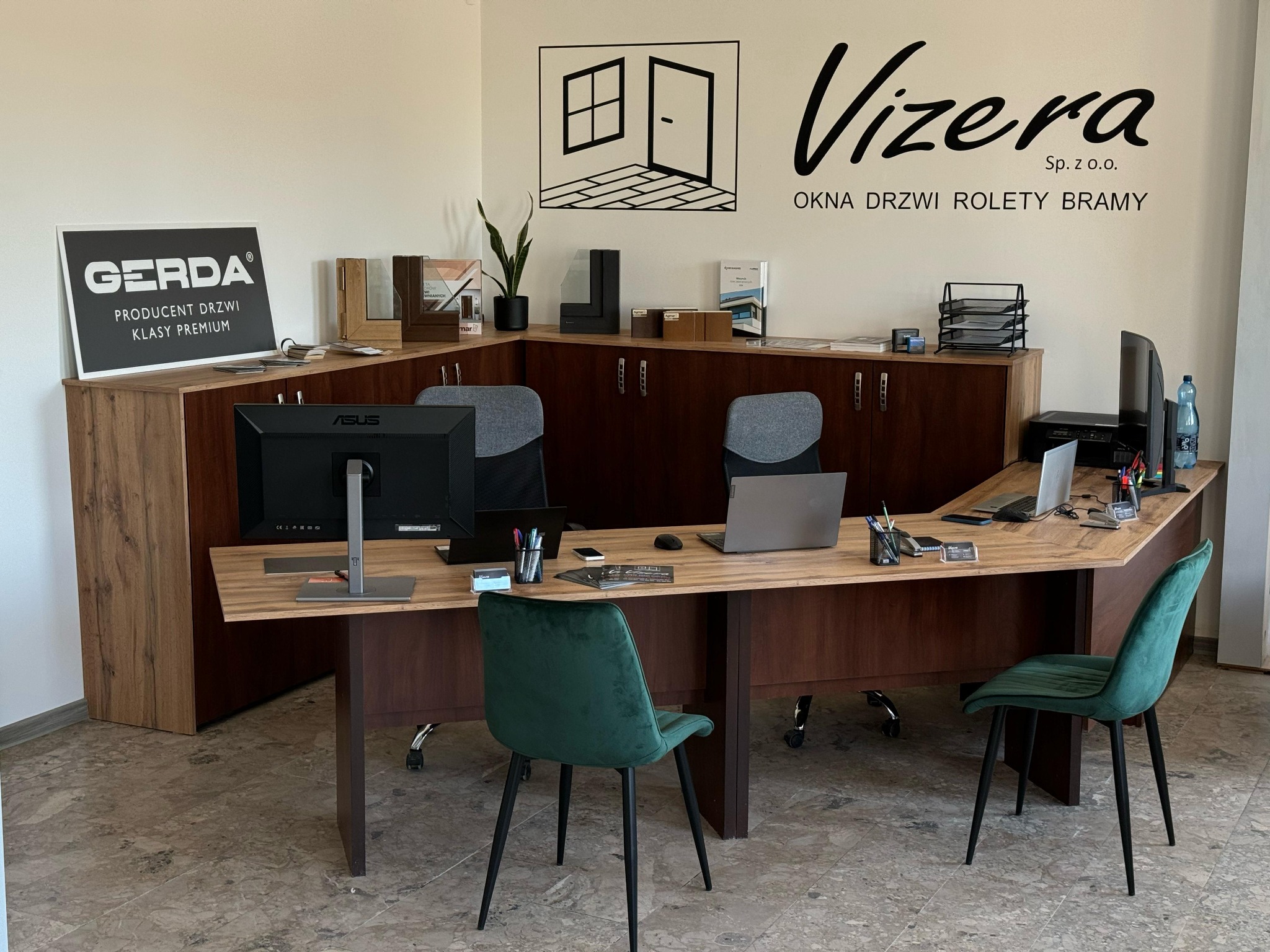 Biuro firmy Vizera z ekspozycją okien, drzwi, rolet i bram. Widoczne biurko z komputerami, krzesła i logo Gerda, producenta drzwi klasy premium.