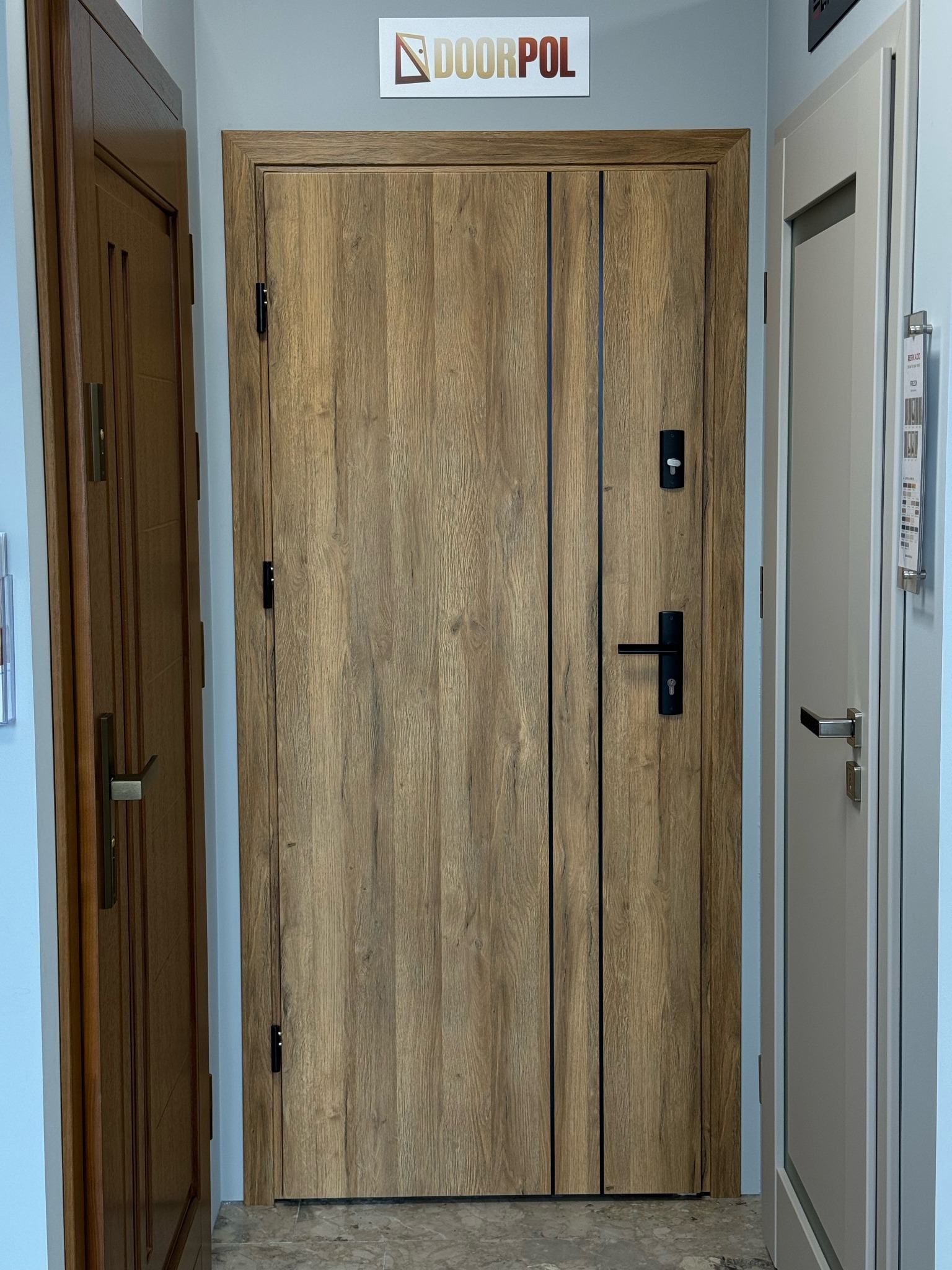 Drewnopodobne drzwi marki Doorpol z czarnymi akcentami, widoczne między innymi drzwiami w ekspozycji. Proste, matowe wykończenie, nowoczesny design.