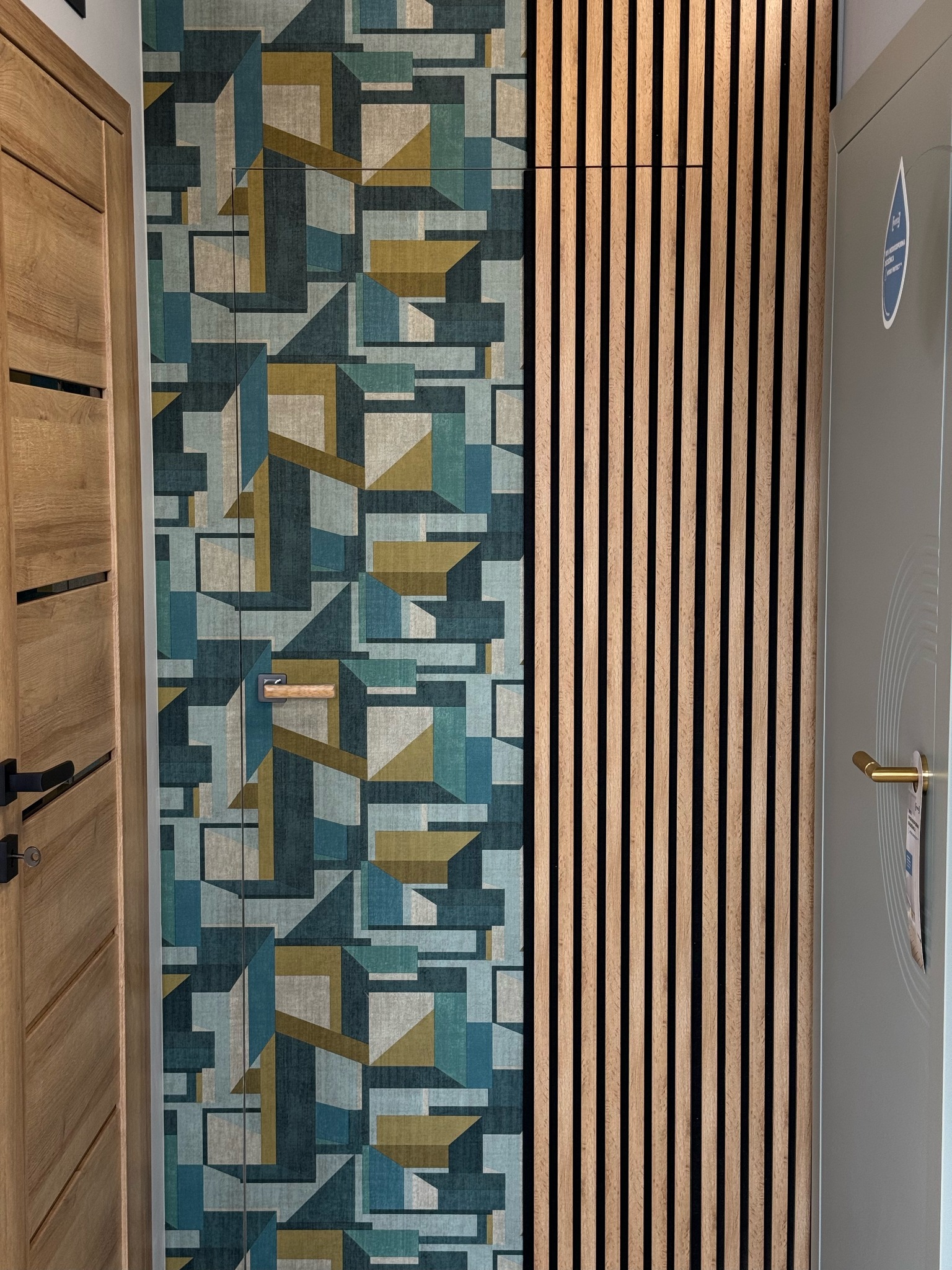Kompozycja trzech drzwi o różnym wykończeniu: drewniane z frezami, wzorzyste w geometryczne kształty oraz gładkie, szare z pionowymi lamelami.