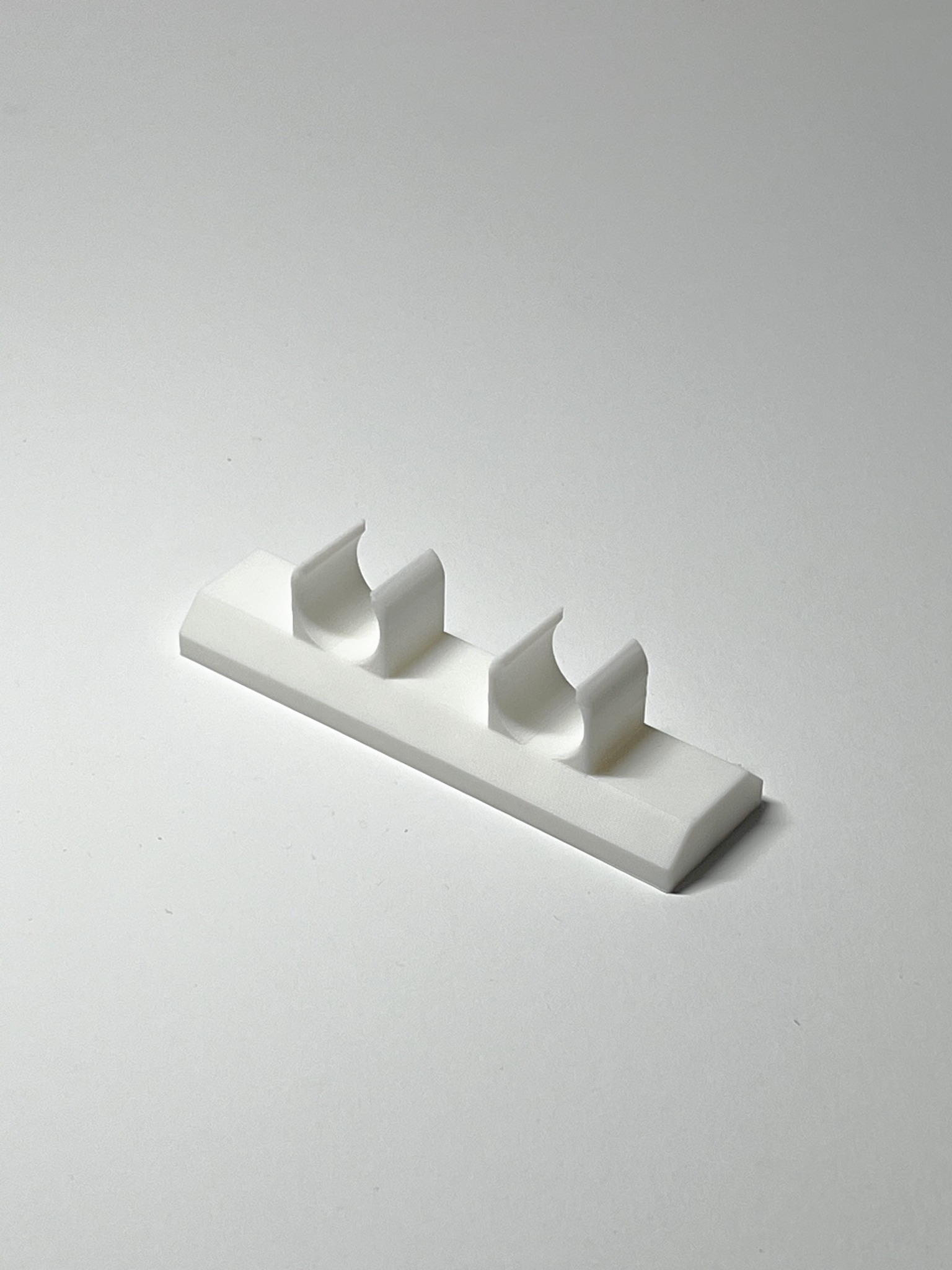 Biały uchwyt na rurki, wydrukowany w 3D w Łagiewnikach. Precyzyjne wykonanie, gładka powierzchnia. Druk 3D jako usługa.
