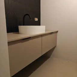 Nowoczesna łazienka: beżowa szafka z umywalką nablatową i czarną armaturą na tle ściany z ciemnych, podłużnych płytek. Minimalistyczny design.