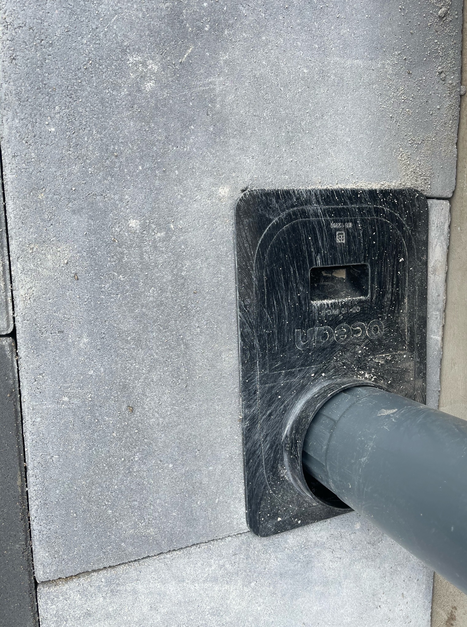 Szara kostka brukowa z uszczelnieniem przepustu rurowego Unico, widok z góry, detale montażu.