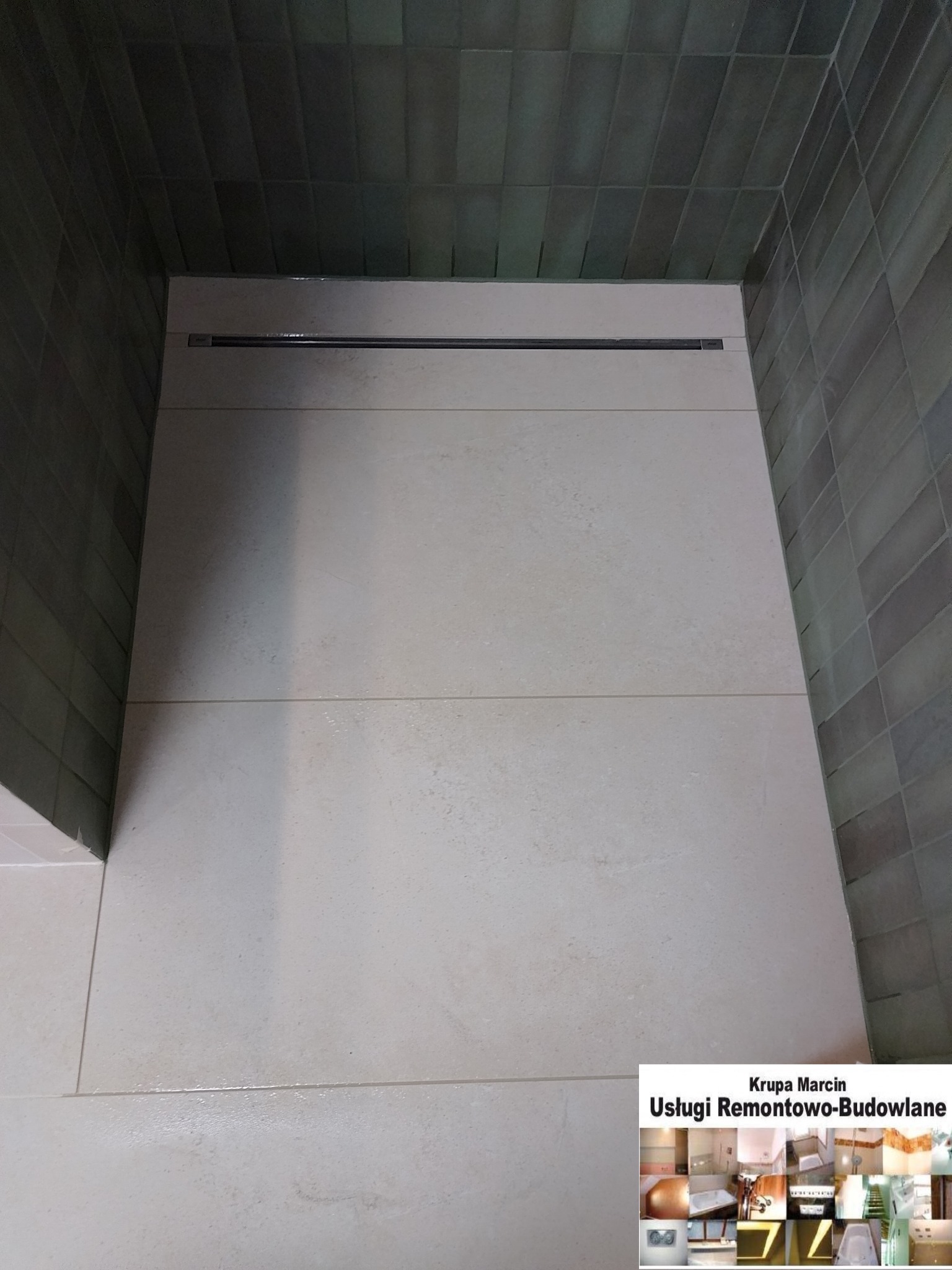 Ukończona kabina prysznicowa z odpływem liniowym, wyłożona jasnymi, kwadratowymi płytkami podłogowymi i ciemnymi, prostokątnymi płytkami ściennymi w odcieniach szarości.