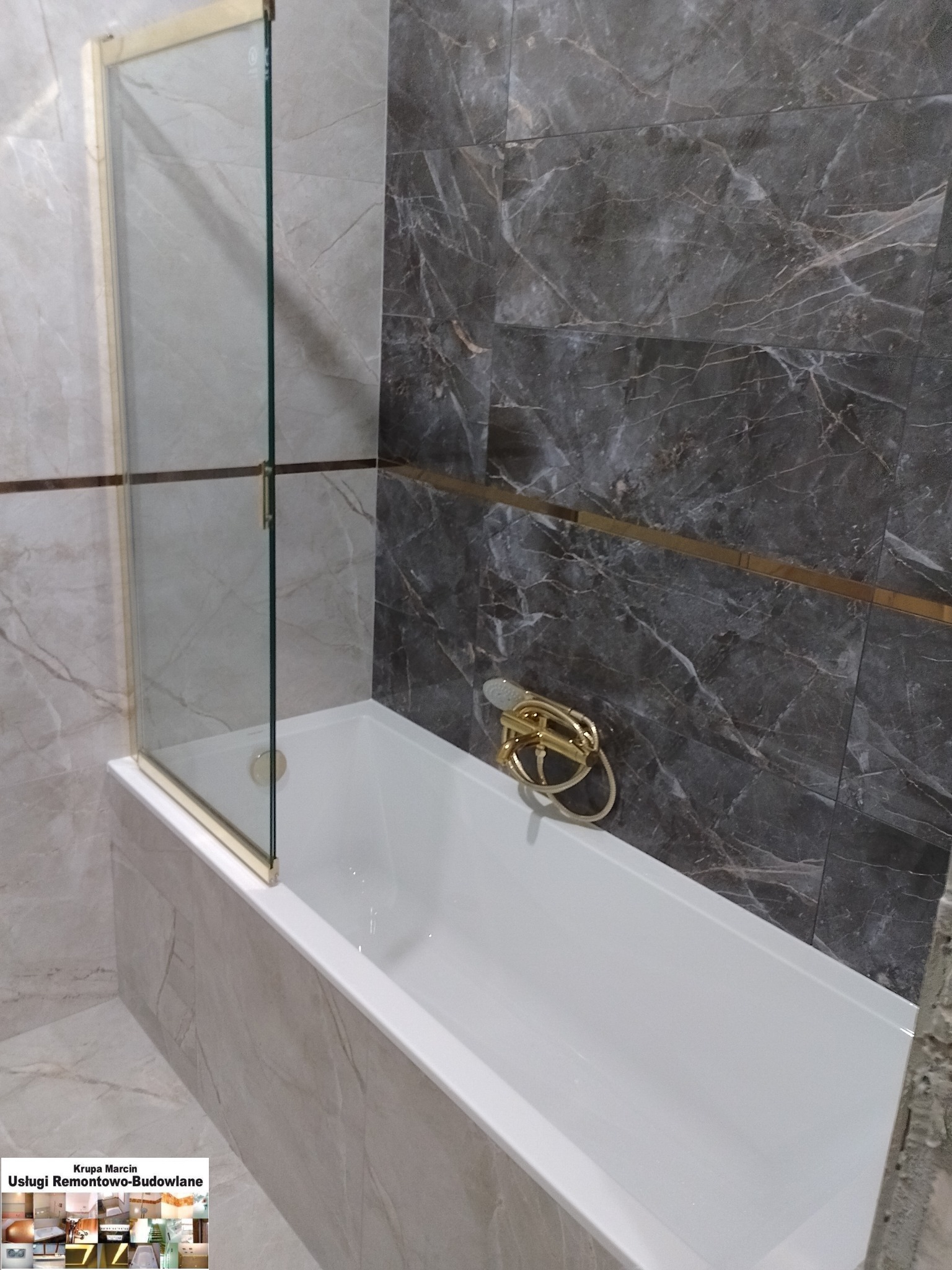 Wykończona łazienka: wanna obudowana marmurowymi płytkami, szklany parawan z złotymi detalami i bateria w kolorze złota, marmurowe płytki na ścianie.