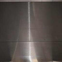 ABK-Reinigungsunternehmen - Metalowa podłoga w przestrzeni ładunkowej, z antypoślizgową fakturą i widocznymi łączeniami płyt, oświetlona centralnie, ukazująca czystość i gotowość do użytku.