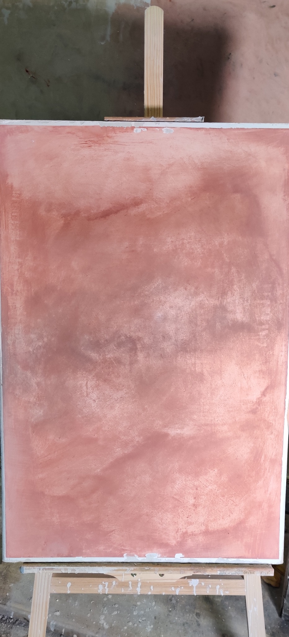 Różowa ściana z efektem dekoracyjnym na sztaludze, ukazująca unikalną fakturę i odcienie. Widoczne ślady pędzla i nieregularne wzory.