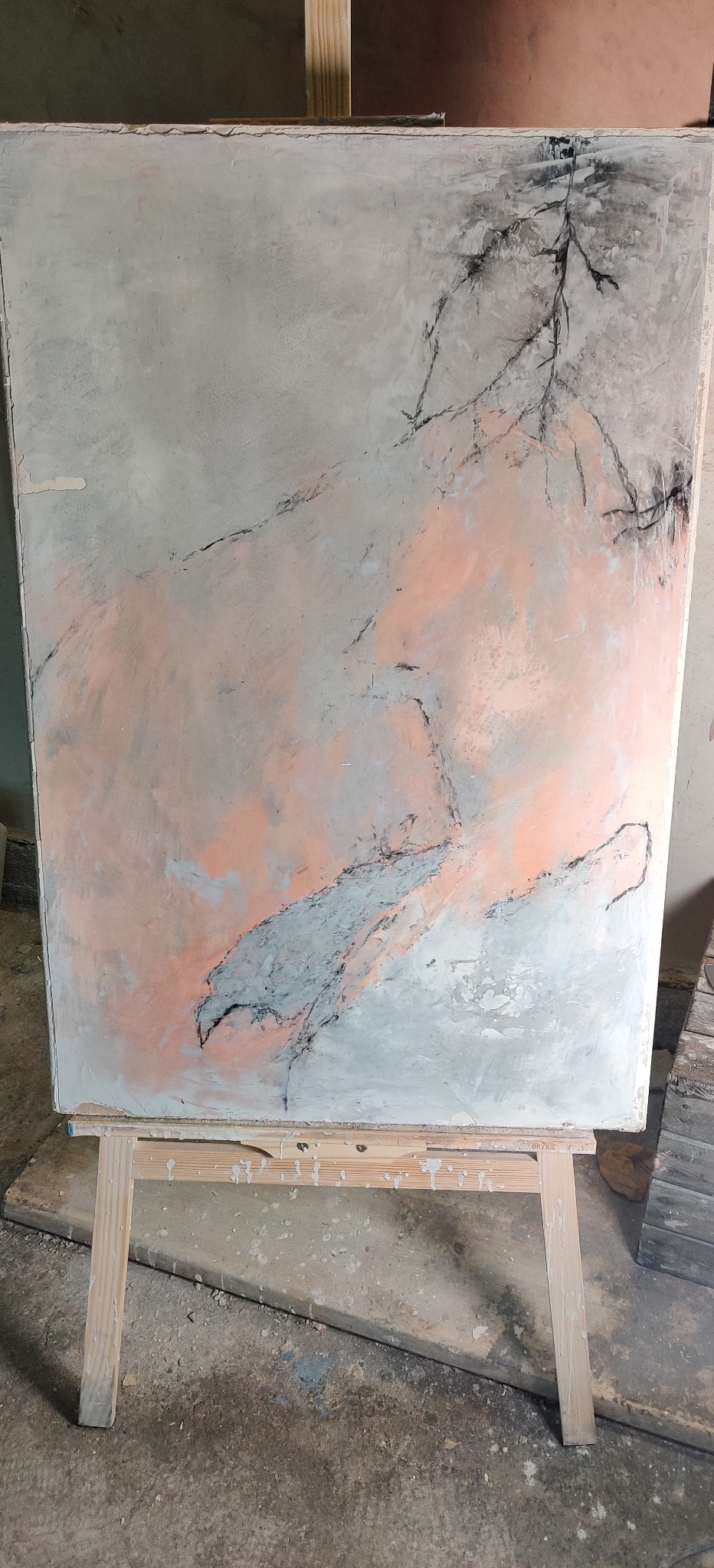 Praca artystyczna na płótnie na drewnianym stojaku. Abstrakcyjne wzory w odcieniach szarości, różu i czerni. Widoczne ślady farby i faktura powierzchni.