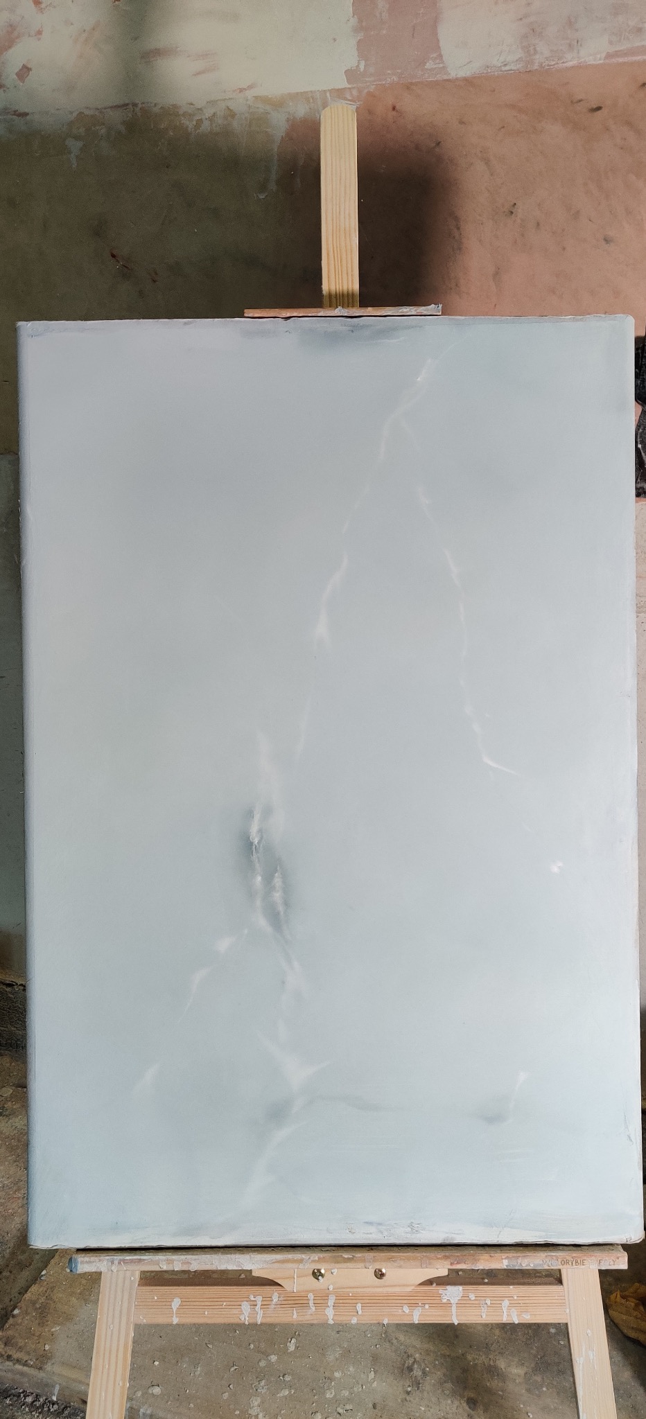 Ściana po szpachlowaniu, imitująca marmur, na drewnianym stojaku. Widoczne niedoskonałości ściany w tle. Delikatne żyłki imitujące marmur na gładzi.