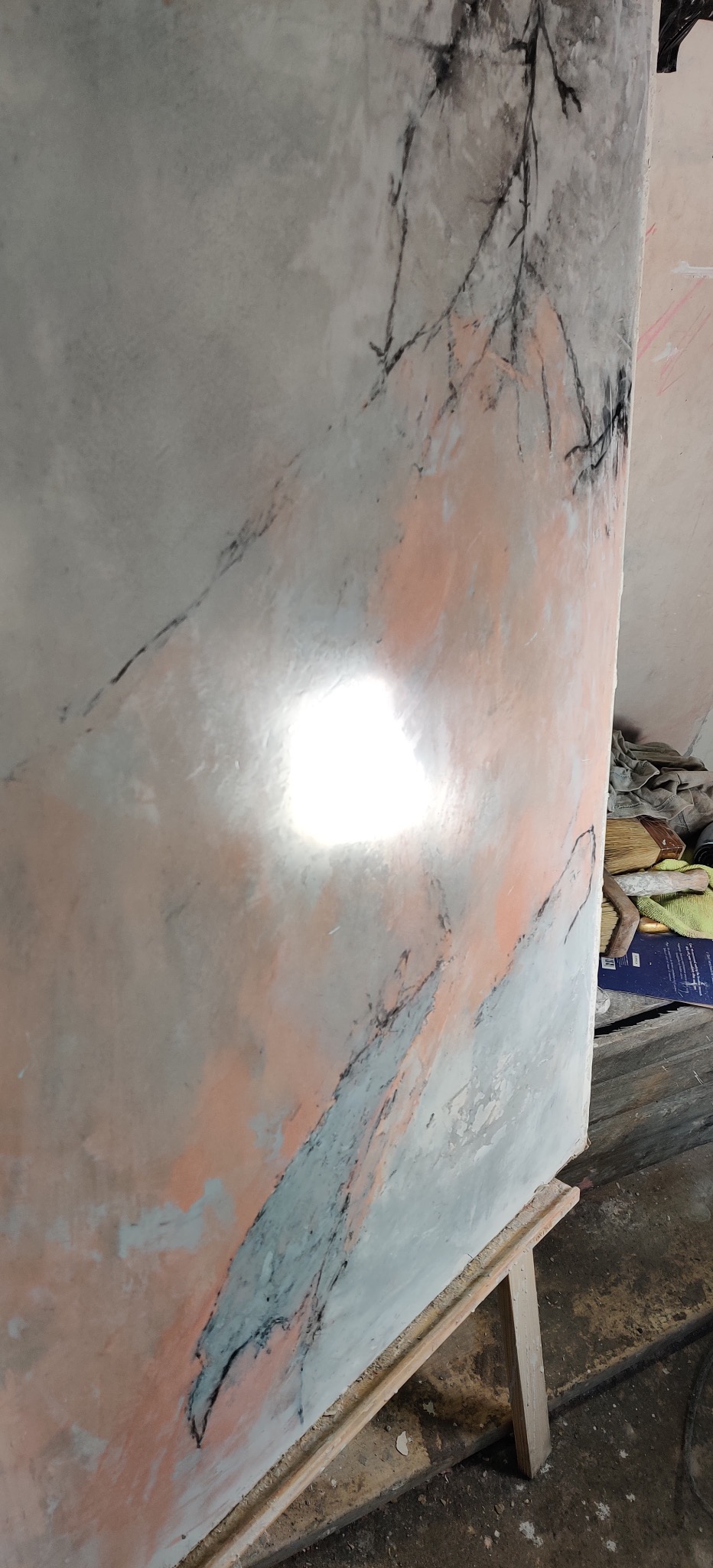 Ściana z efektem dekoracyjnym imitującym marmur w odcieniach szarości, błękitu i różu, z dodatkowymi czarnymi liniami przypominającymi gałązki drzew.