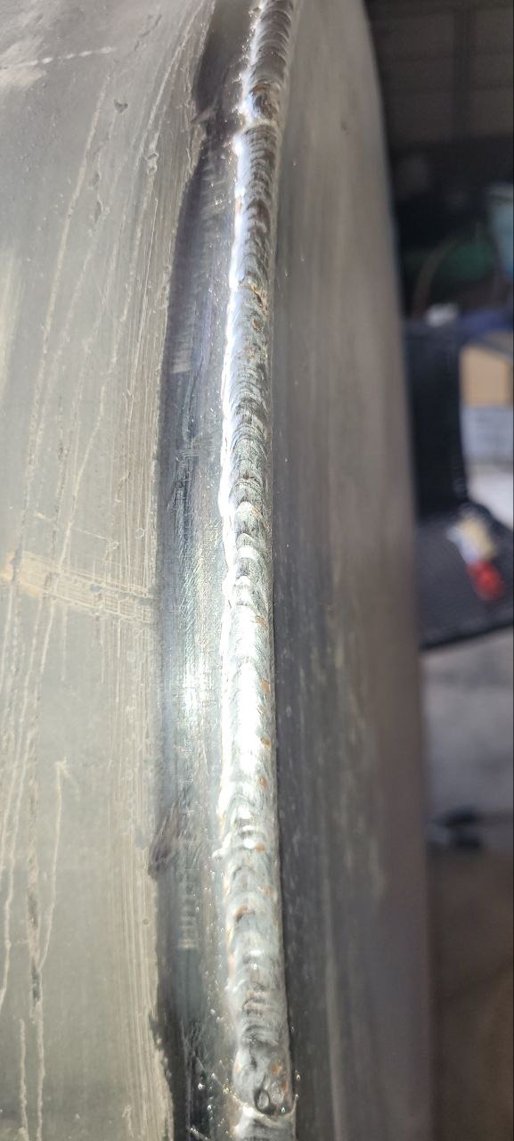 Szlif spawalniczy na metalowej powierzchni. Widoczne ślady po obróbce i charakterystyczna faktura spawu. Detal z bliska ukazuje precyzję wykonania.