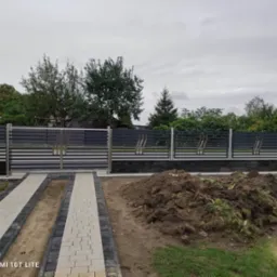 Nowoczesna brama wjazdowa z poziomymi przęsłami i stalowymi słupkami, uzupełniona o segmenty ogrodzenia. Na pierwszym planie ścieżka z kostki brukowej.