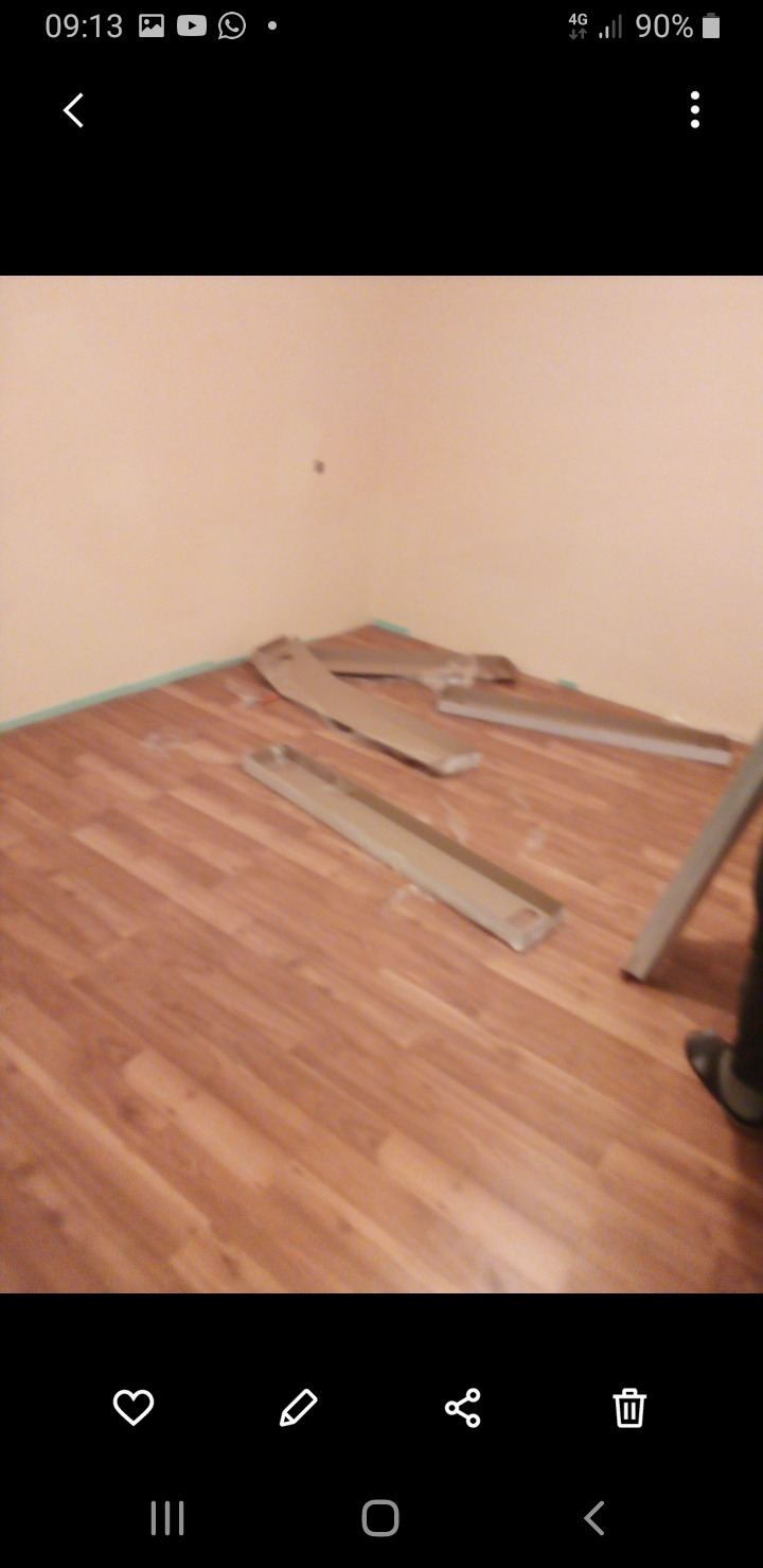 Układanie paneli podłogowych w rogu pokoju, widoczne listwy przypodłogowe. Prace remontowe w Wodzisławiu Śląskim. Wykończenie wnętrz.