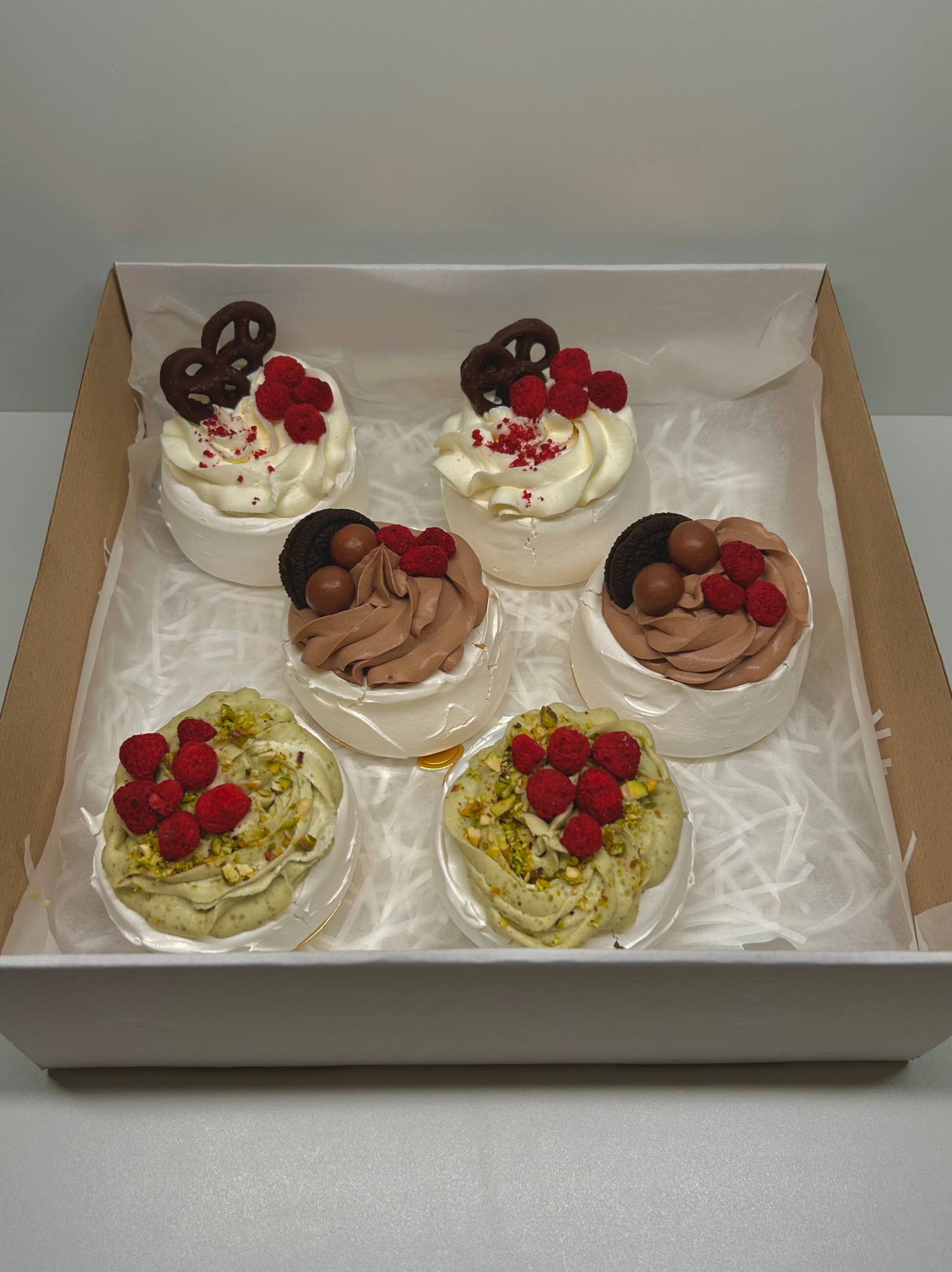 Eleganckie mini bezy w pudełku, każda z innym kremem i owocami: pistacjowe z malinami, czekoladowe z Oreo, śmietankowe z preclami. Idealne na prezent.