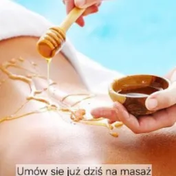 Aplikacja miodu na plecy klienta za pomocą nabieraka i miseczki podczas zabiegu. Jasne tło, relaksacyjny charakter.