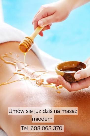 Aplikacja miodu na plecy klienta za pomocą nabieraka i miseczki podczas zabiegu. Jasne tło, relaksacyjny charakter.