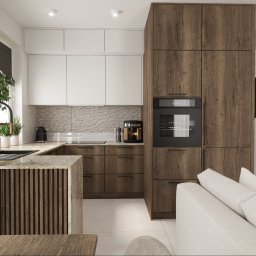 BLANKY STUDIO Pracownia Architektury Wnętrz - Nowoczesna kuchnia z drewnianymi frontami, białymi szafkami górnymi i wyspą z blatem z kamienia. W tle widoczny fragment salonu z jasną sofą.
