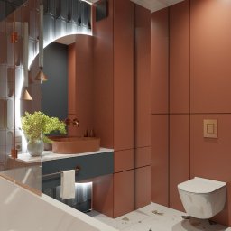 BLANKY STUDIO Pracownia Architektury Wnętrz - Nowoczesna łazienka w odcieniach terakoty i szarości, z okrągłym lustrem podświetlonym LED i umywalką w kolorze rdzy. Minimalistyczny design i eleganckie wykończenie.