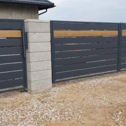 Daniel Zakrzewski Ogrodzenia - Nowoczesna brama wjazdowa z szarego metalu z poziomymi panelami i drewnianymi akcentami, osadzona na betonowych słupkach z szarej kostki.