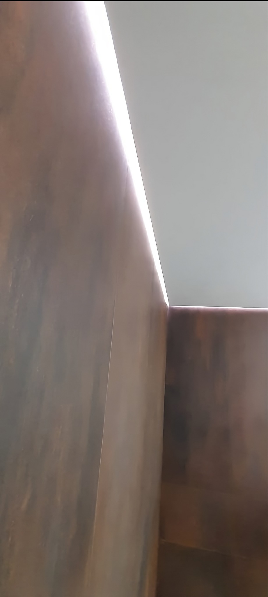 Nowoczesna łazienka: ciemne płytki imitujące rdzę, podświetlony sufit LED. Minimalistyczny design.