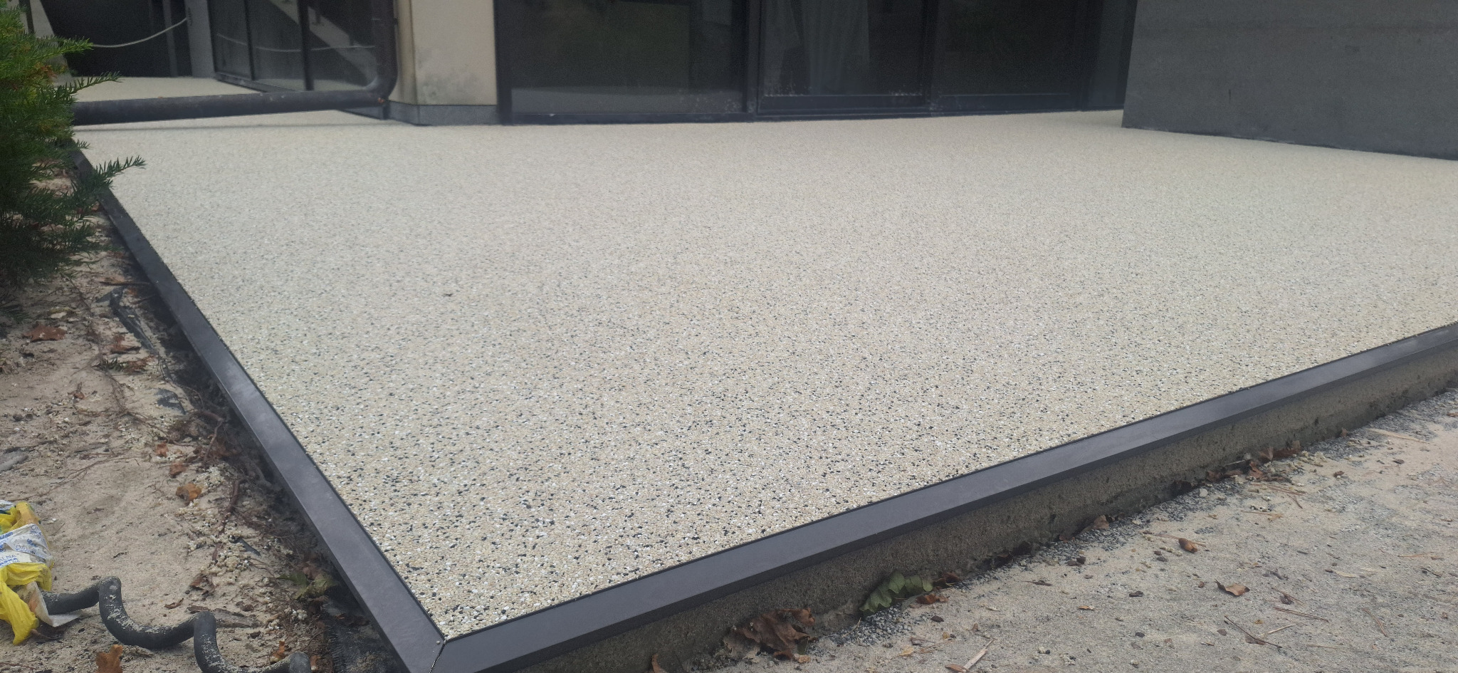 Jasna, drobnoziarnista powierzchnia z żywicy w Siedlcach, obramowana czarną listwą. Widoczne fragmenty otoczenia.