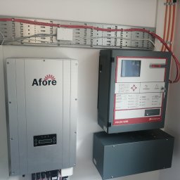 HTControl Hryhorii Tokarenko - Szara centrala alarmowa Polon 4200 z ekranem i przyciskami, obok srebrny falownik Afore, kable w korytku. Elementy instalacji alarmowej wewnątrz budynku.