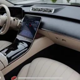 Luksusowe wnętrze Mercedesa S-klasy z beżową tapicerką skórzaną, widoczne z perspektywy kierowcy w Rzeszowie. Eleganckie wykończenie deski rozdzielczej i duży ekran dotykowy.