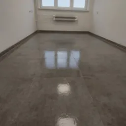 Pokój po remoncie z szarymi płytkami na podłodze, białe ściany i okno z grzejnikiem. Widok na gładką posadzkę z odbiciami światła okiennego.