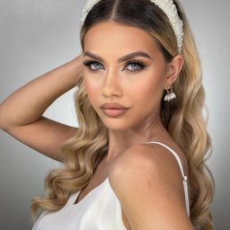 Przedsiębiorstwo Handlowo-Usługowe DAWID KREPS - Portret kobiety z blond włosami, w białej sukience i perłowej opasce, prezentującej profesjonalny makijaż z wyraźnie podkreślonymi oczami i ustami.