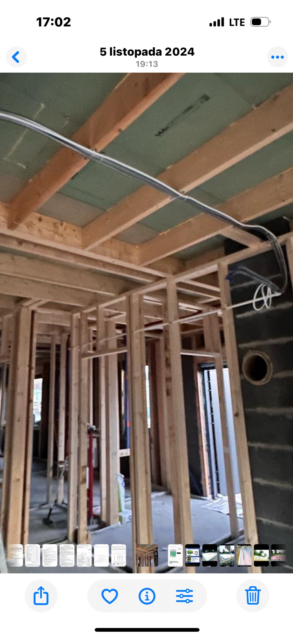 Wnętrze domu szkieletowego w trakcie budowy. Widoczne drewniane ramy ścian, stropu i instalacje elektryczne. Stan surowy zamknięty, etap przed wykończeniem.