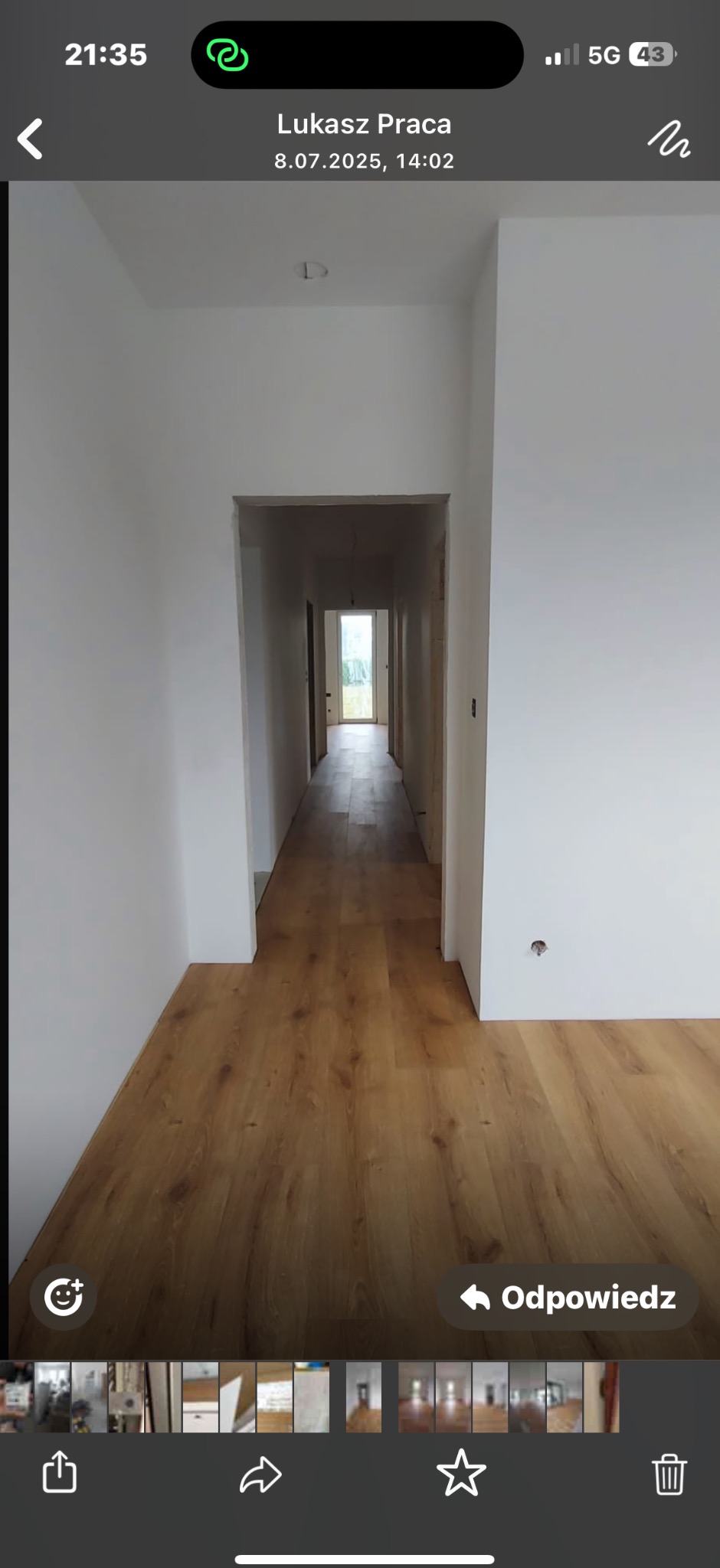 Korytarz po remoncie z ułożonymi panelami podłogowymi w odcieniach brązu i świeżo pomalowanymi ścianami na biało. Widok w głąb korytarza, wpadające światło dzienne.