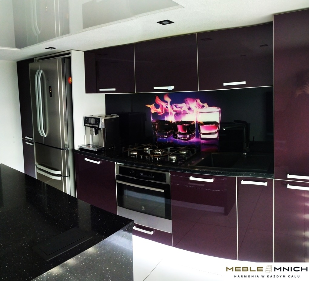 Nowoczesna kuchnia w odcieniach śliwki z połyskującymi frontami, czarnym blatem i panelem szklanym z motywem płomieni. Widoczny sprzęt AGD i wyspa z czarnym, błyszczącym blatem.