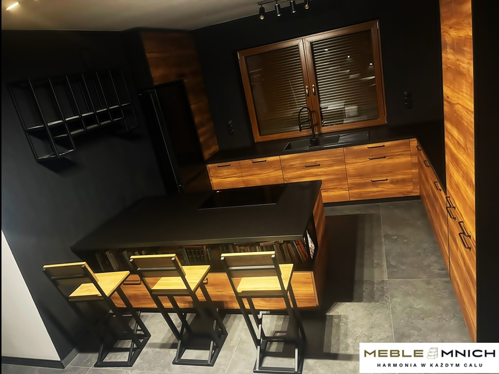 Nowoczesna kuchnia na wymiar z drewnianymi frontami i czarnym blatem, wyspa z hokerami, czarne ściany i metalowe półki. Oświetlenie punktowe.