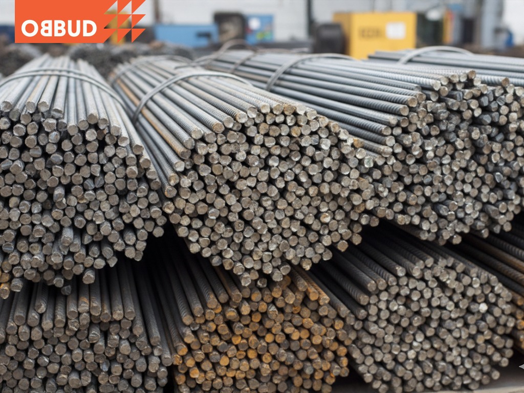 Sztaple wiązek żebrowanej stali zbrojeniowej na składzie budowlanym, widoczne przekroje prętów i wiązania. Ujęcie z bliska, oświetlenie magazynowe.