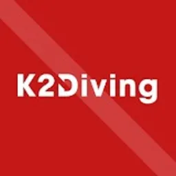 Logo K2 Diving na czerwonym tle z ukośnym białym pasem. Litera 'D' w 'Diving' stylizowana na nurka. Minimalistyczny design, wyraźna typografia.