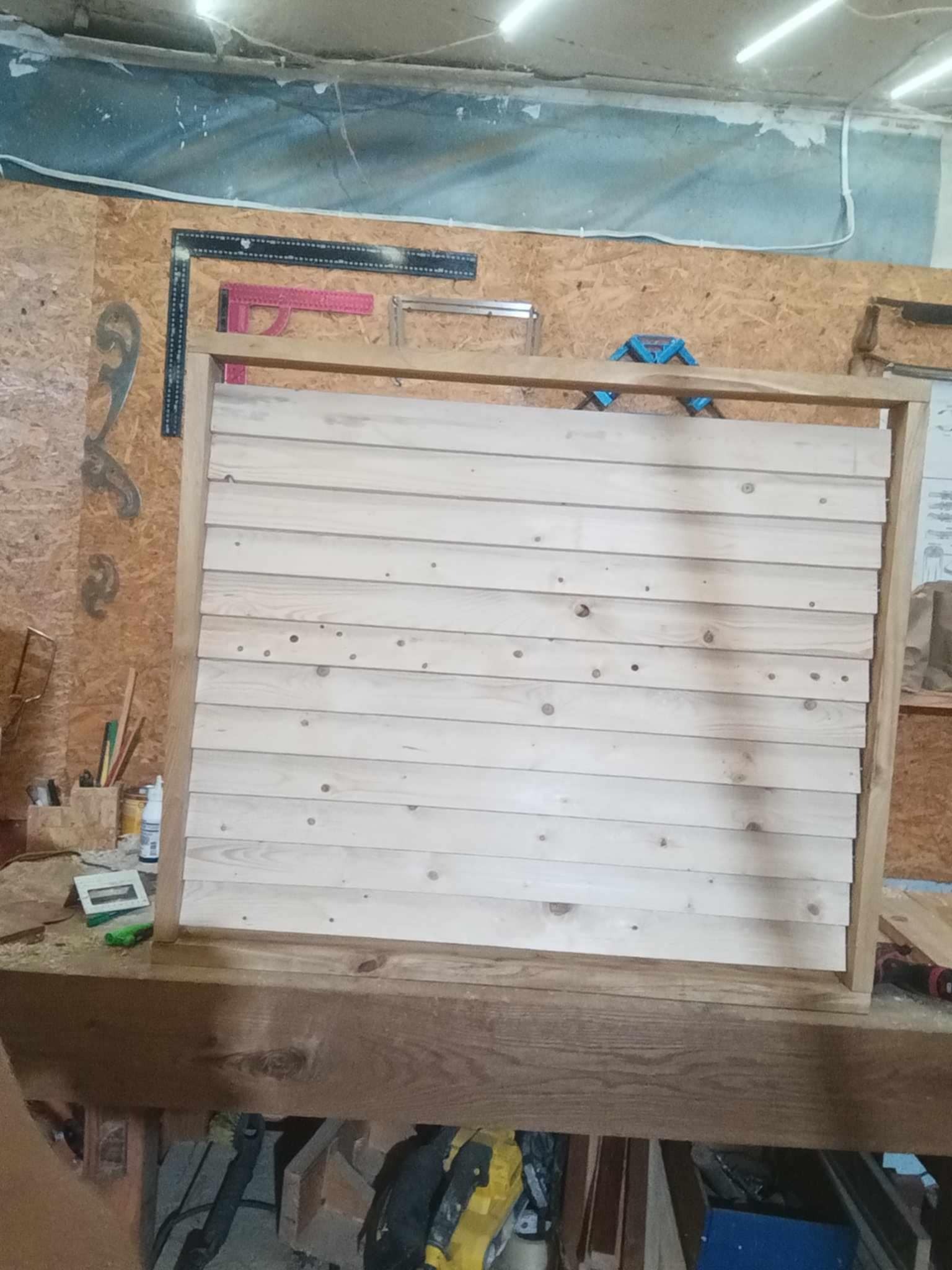 Drewniana konstrukcja z desek w warsztacie w Lubartowie. Rama z poziomymi deskami, narzędzia w tle. Praca stolarska w toku, widoczne elementy montażowe.