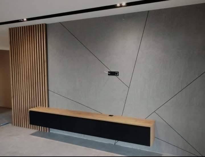 Nowoczesne wnętrze: szara ściana z geometrycznym wzorem, drewniane lamele i podwieszana szafka RTV z drewnianym blatem. Minimalistyczny design.