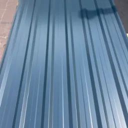 Szara blacha trapezowa z wyraźnym cieniowaniem, ułożona na drewnianym podłożu, widok z góry, podkreślający symetrię i regularność profilu.