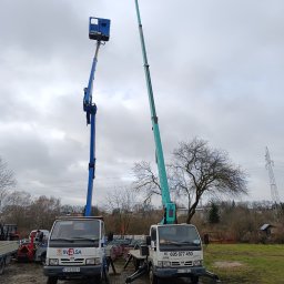 FUH KAMANI Kamil Walczak - Dwa podnośniki koszowe na białych samochodach dostawczych, jeden niebieski, drugi zielony, stojące na placu pod pochmurnym niebem. Widoczne podpory stabilizujące.