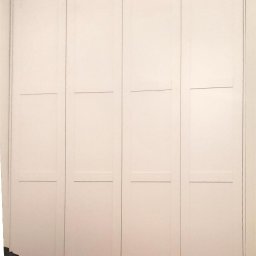 LE WOOD - Biała, czterodrzwiowa szafa wnękowa z panelami, wbudowana od podłogi do sufitu. Minimalistyczny design, jasne wnętrze, widoczne detale wykończenia.